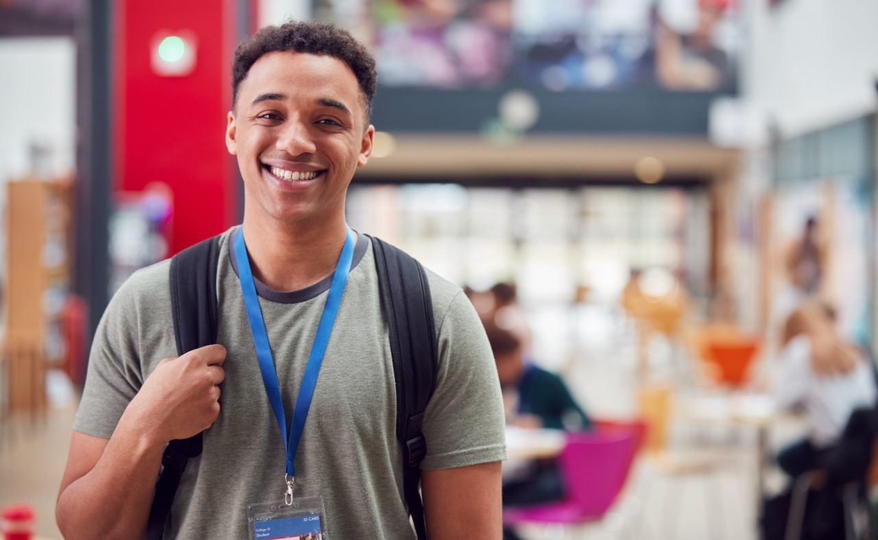 portrait of smiling male college student in busy communal campus building.jpg